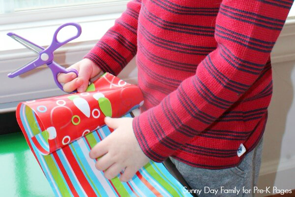 child cutting wrapping paper with scissors