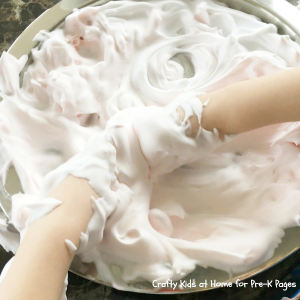 hands engaging in sensory play by playing in shaving foam