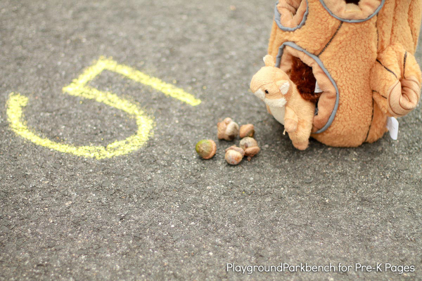 number five in chalk on sidewalk with 5 acorns