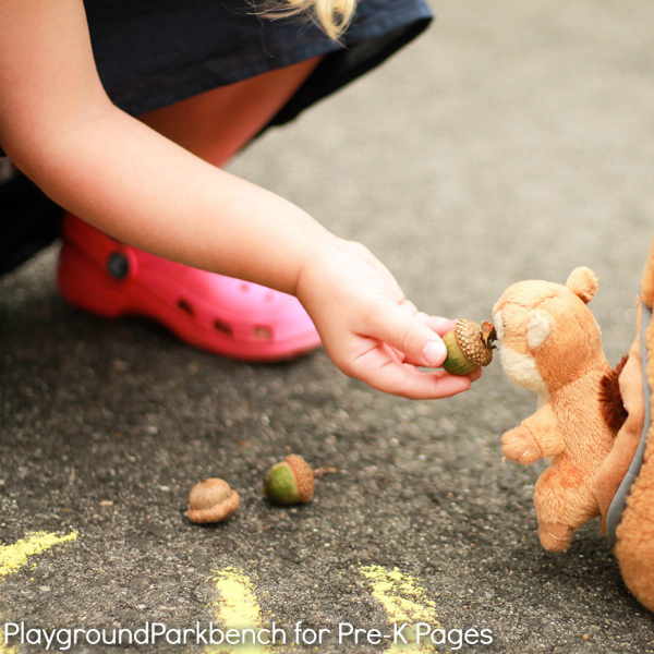 little girl feeding pretend squirrel an acorn
