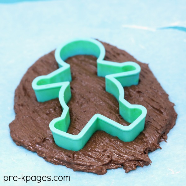 gingerbread cookie cutter placed into dough 