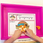 a child making a face on a scarecrow mat with play dough